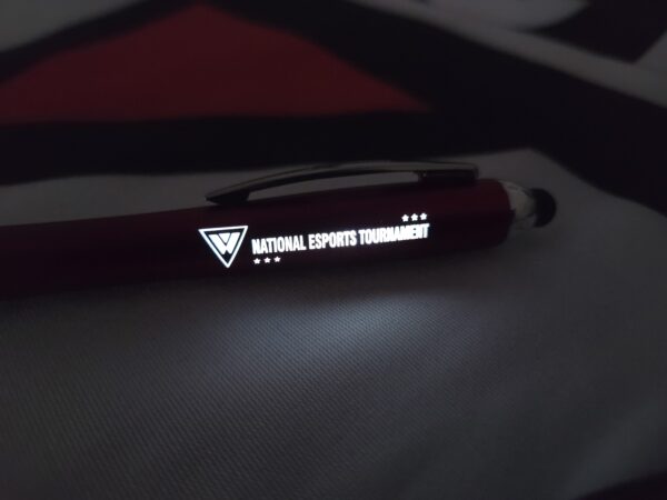 The same pen shown in a dark environment, with the NEST logo brightly illuminated in white LED light.